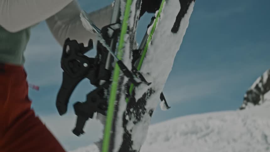 Lady picks up her skis from the snow on a sunny day