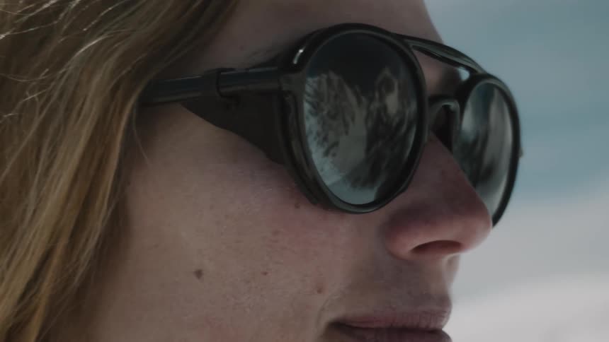 Portrait of a woman in a natural environment wearing sunglasses with mountain reflections