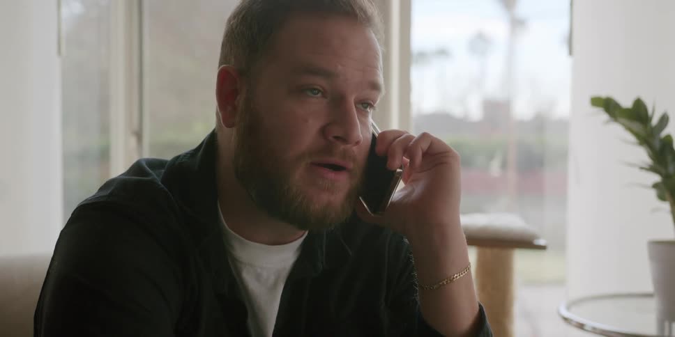 A man talking on phone while sitting on a chair indoor