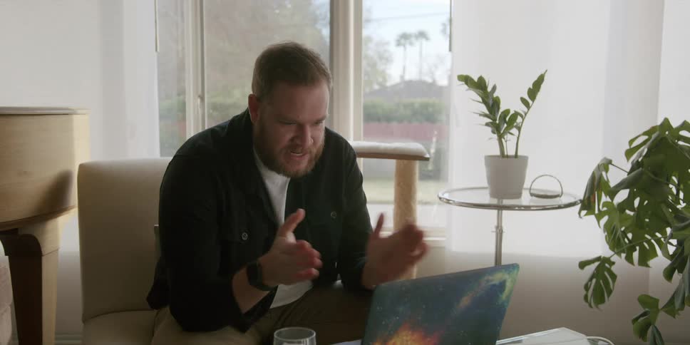 A man talking on a video call through a laptop in the living room