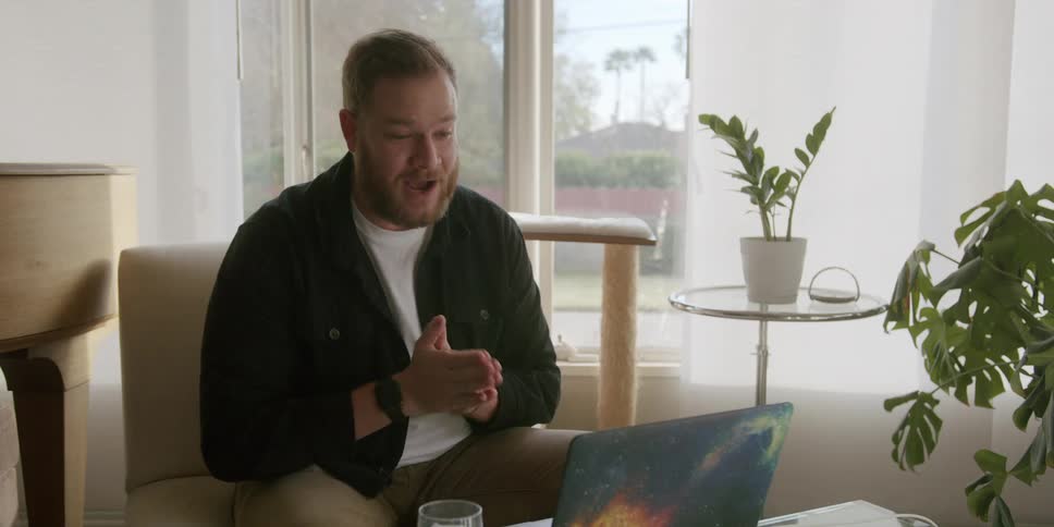 A man excitedly talking on a video call through a laptop in the living room