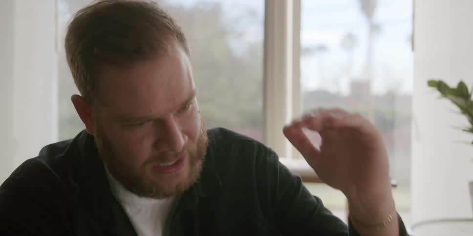 A man sitting in a room talks and gestures