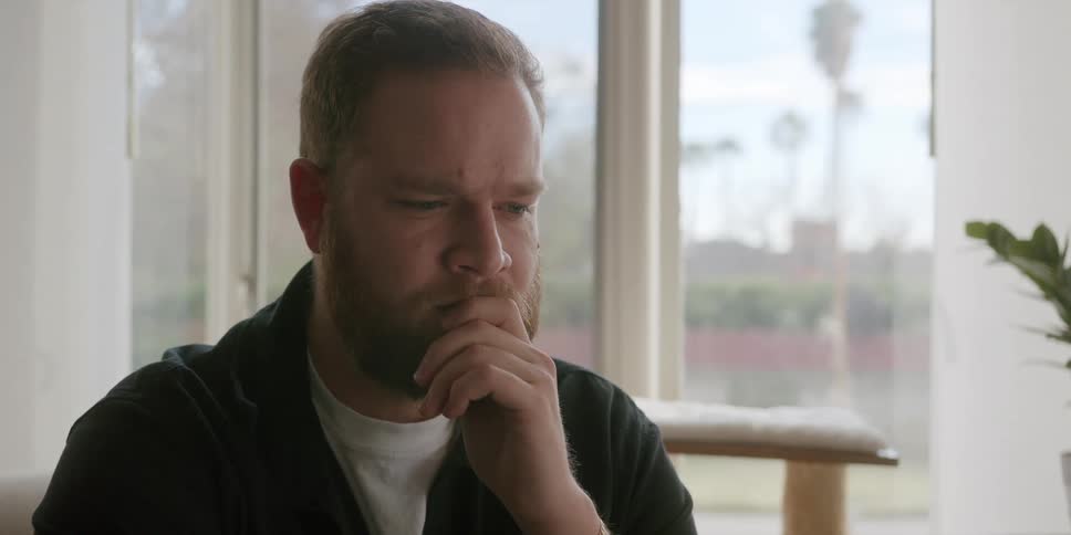 A man is thinking as he rubs his beard