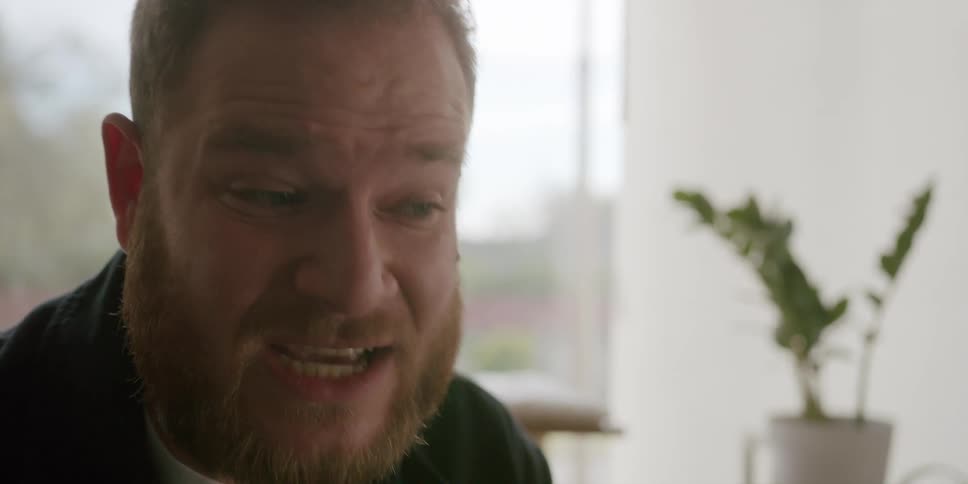 Close up of the face of a bearded man explaining something