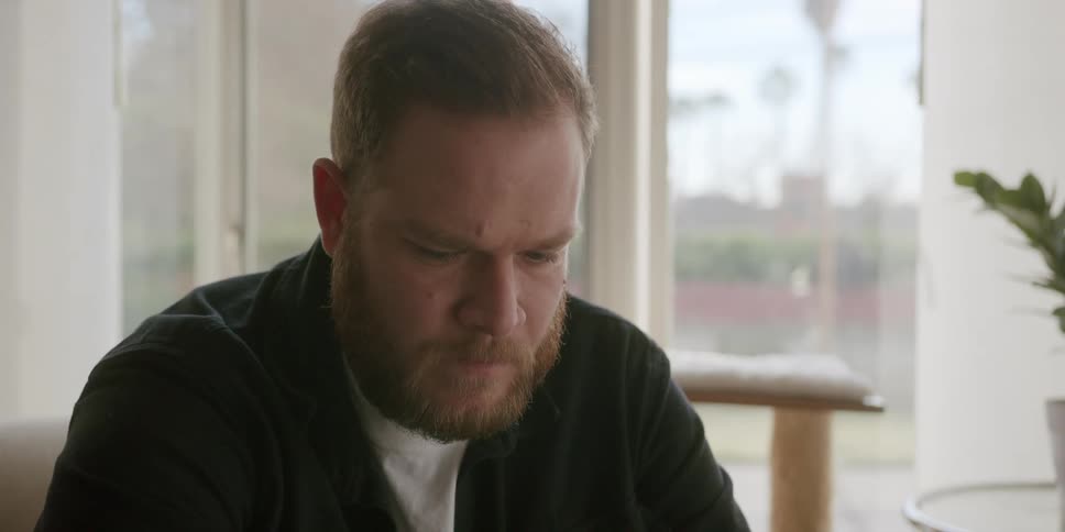 Young bearded man drinks a glass of water and starts talking