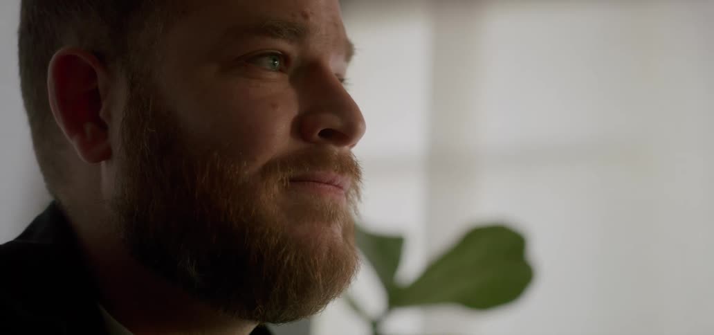 Close up of the face of a bearded man in a room
