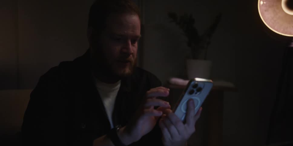 Tired man puts his hands to his eyes after answering the phone at night