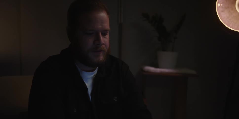 A shaken looking man sits in a living room