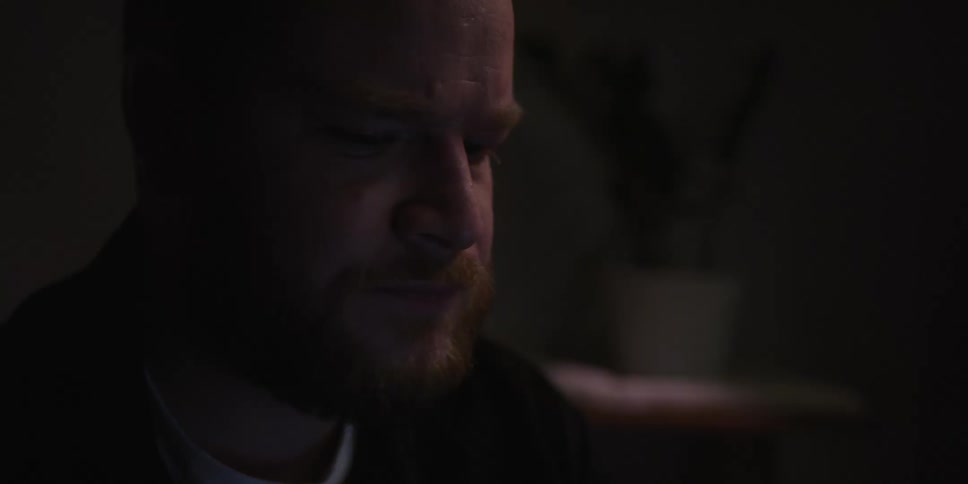 Portrait of a man in a dimly lit room holding a cup of tea