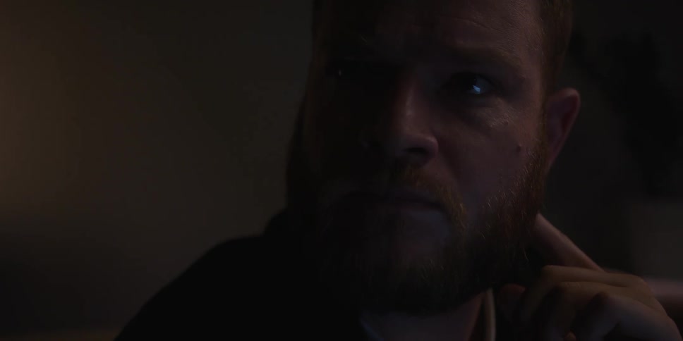 A man looks around while sitting in a dark room