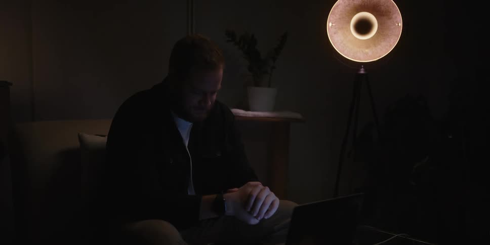 Man sitting on the sofa and having a conversation while facing the laptop