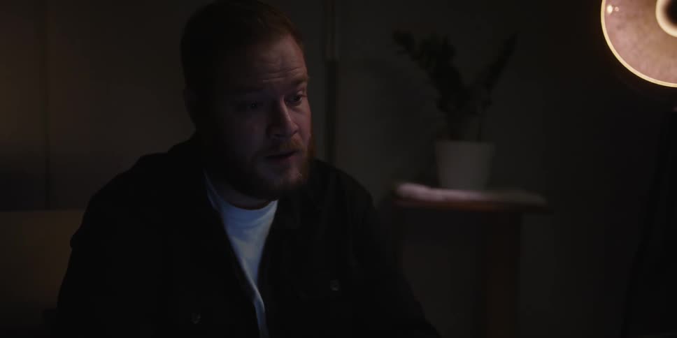 Portrait of a man sitting in a room with low lighting talking