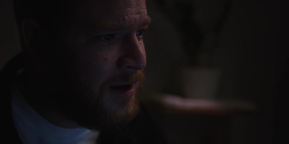 A sad frustrated man talks in a dimly lit room