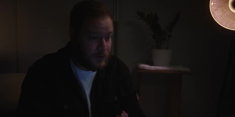 Man talking and gesturing with his arms then having a coffee in a dimly lit room
