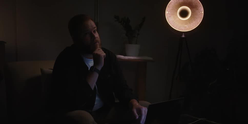 Man sitting on the sofa in a dark room thoughtful and worried