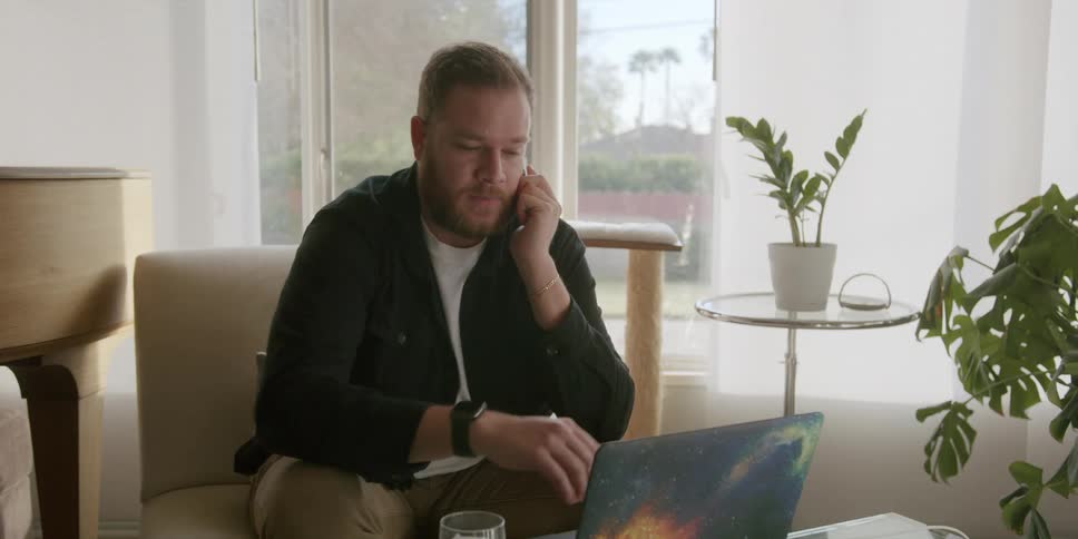 A man sitting in a room talking on a smartphone