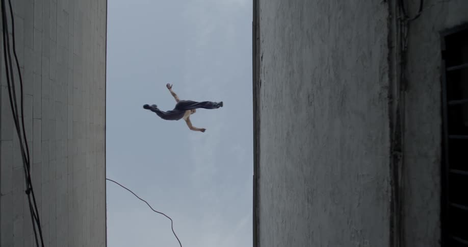 A man leaps from the roof of one building to another