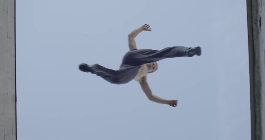 A shirtless man jumps from one roof top to another