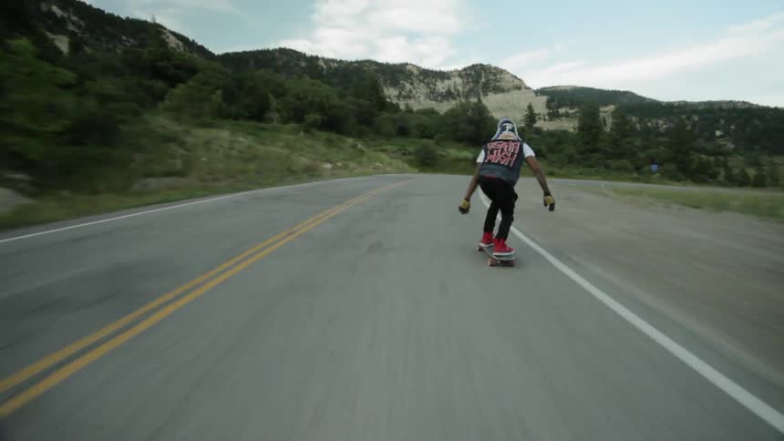 A skateboarder rides down a mountain road at a fast speed