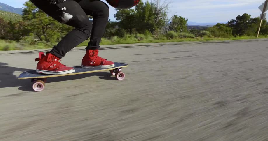 A man riding a skateboard downhill very fast