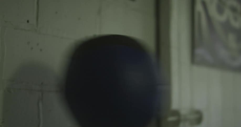 A woman throws a medicine ball against the wall in the gym