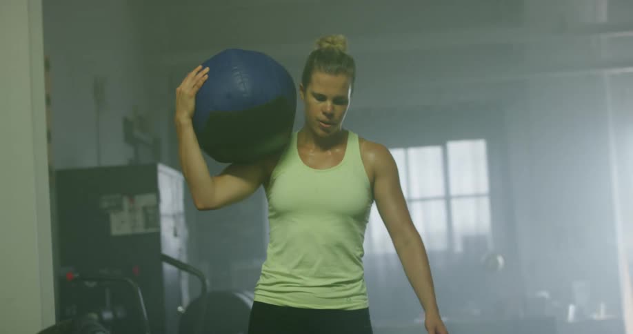 A woman carries a medicine ball in the gym