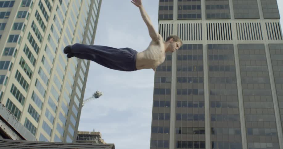 Shirtless man dives off of a building in the city