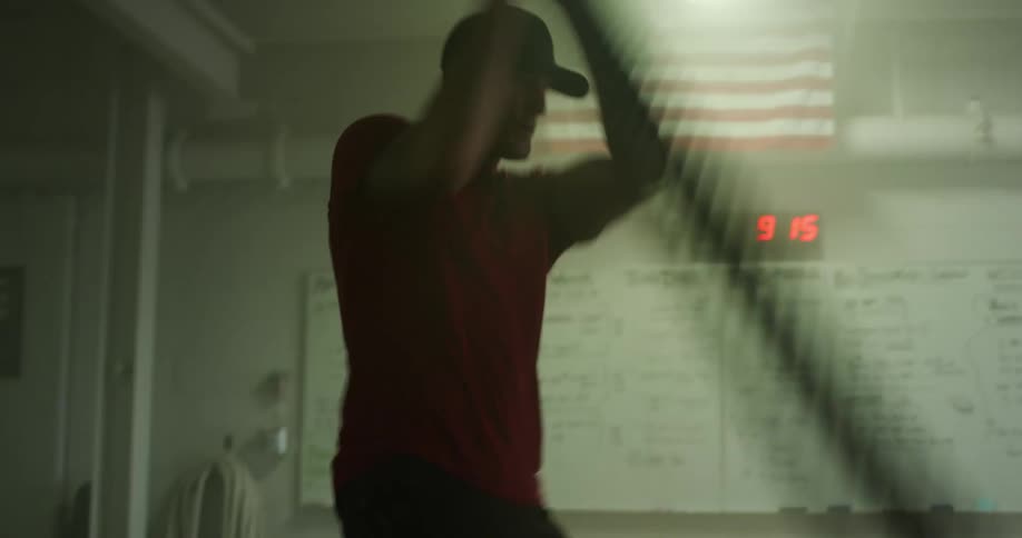 A man exercises in a gym by swinging ropes back and forth