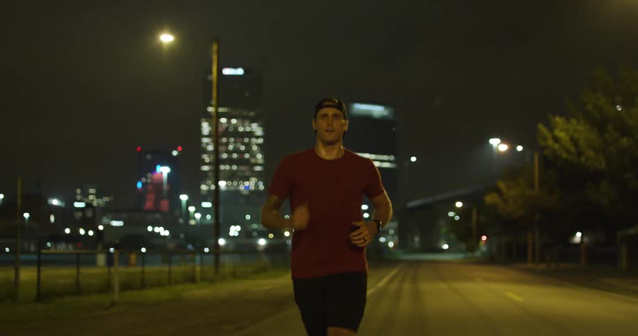 A man jogs down a city street at night