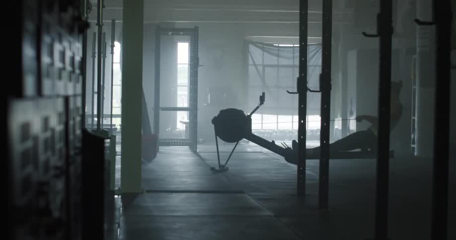 A young woman uses a rowing type machine in a gym