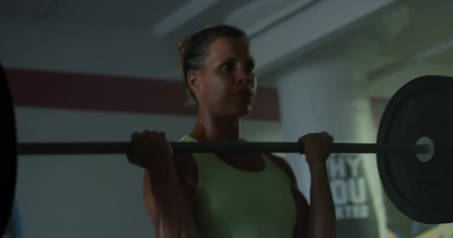 Strong muscular woman lifting weights at the gym