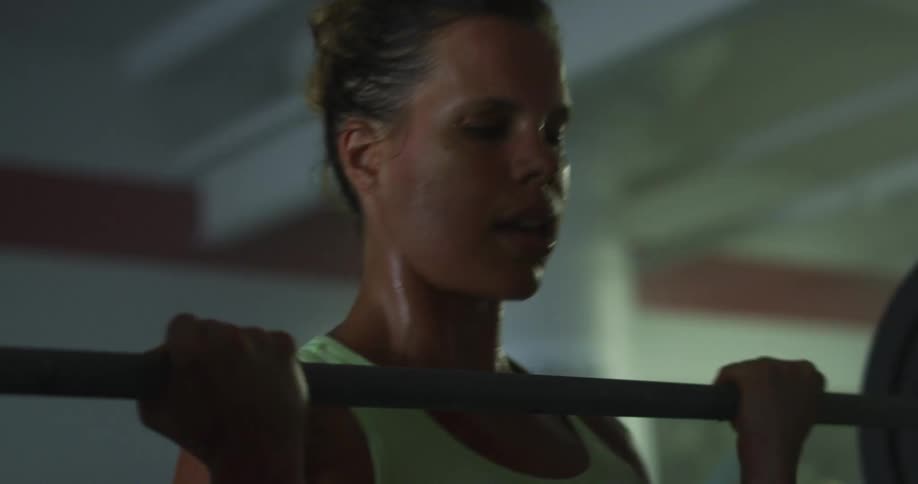 Sweaty and concentrated woman lifting weights with a barbell