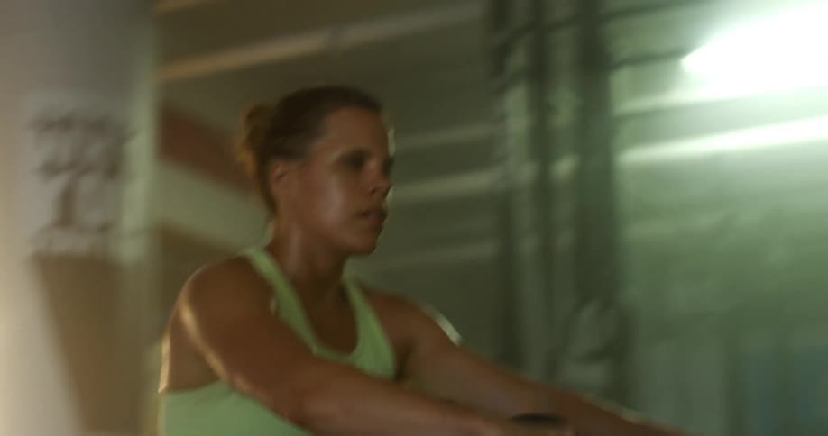 A woman is all sweaty while working out pulling a rope
