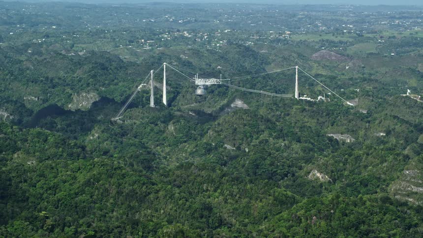 A large radio telescope surrounded by mountains and forests