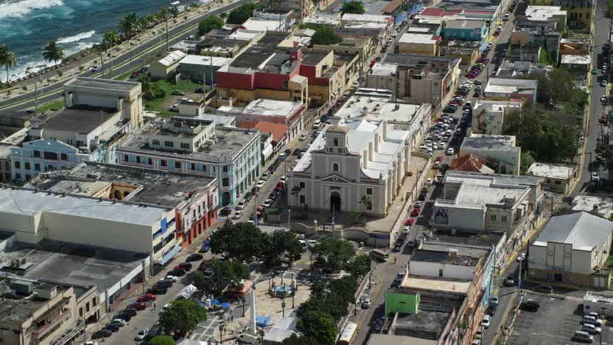 A coastal city with colorful buildings and the cathedral next to the ocean