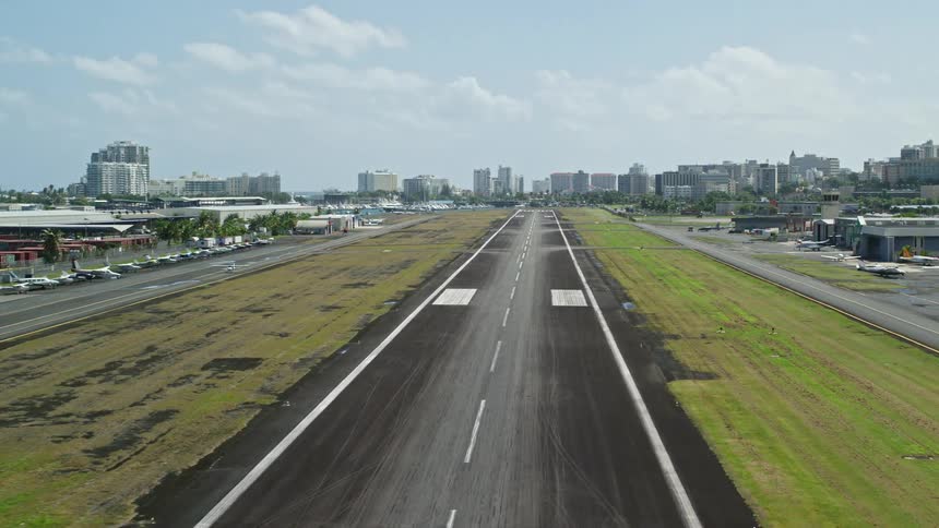 An airport runway with planes and a cityscape in the distance