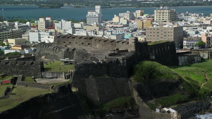 A stone fort facing the sea and behind a city