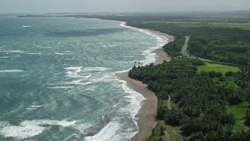 Aerial view of a lush green land next to the ocean