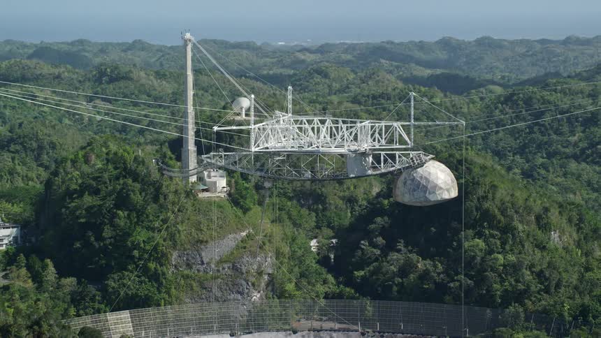 A giant antenna dish is in the mountains