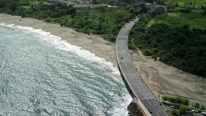 A coastal road with vehicles next to a beach