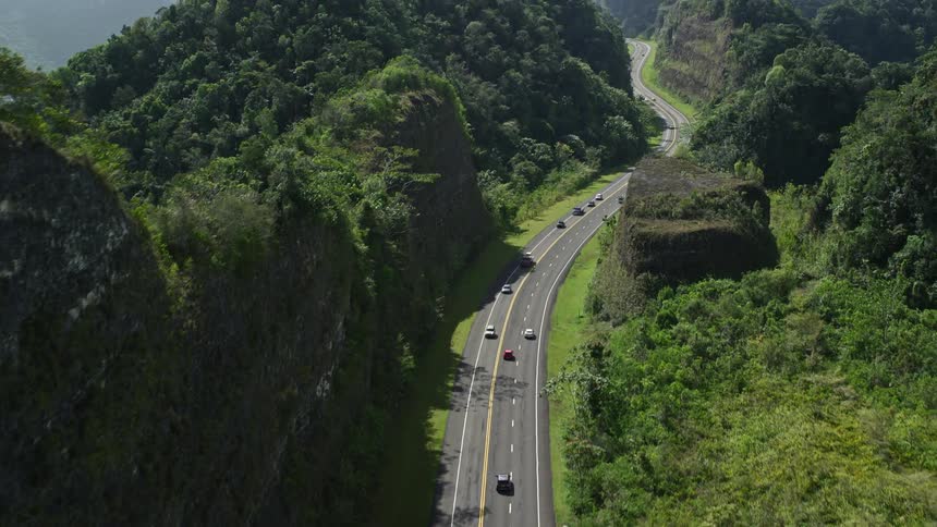 Aerial panorama of a highway with vehicle traffic and surrounding mountain ranges with forests
