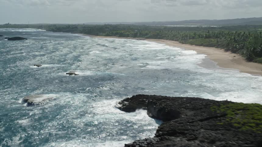 Aerial of a tropical island with rough seas on a sunny day