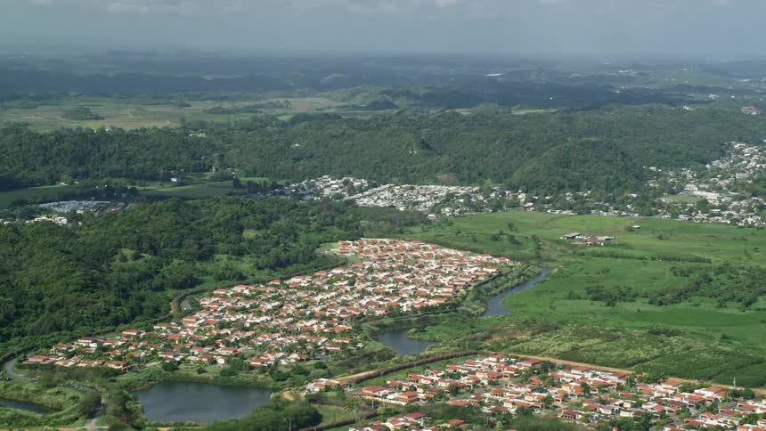 Aerial panorama of a residential city amidst hills and mountains covered in vegetation