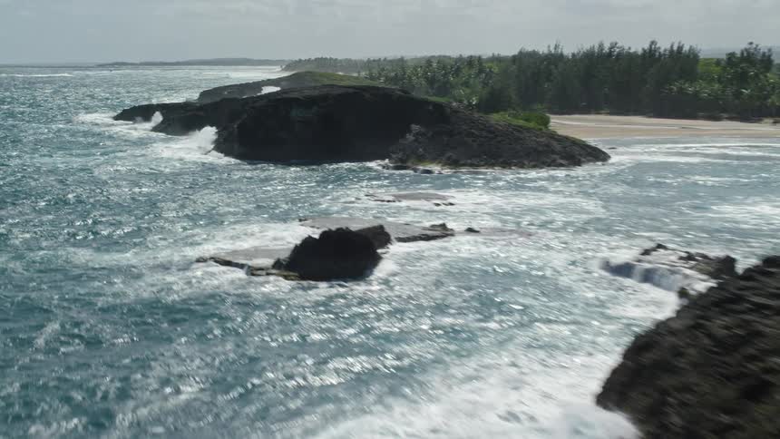 A rough sea where the waves are breaking on huge rocks near the beach