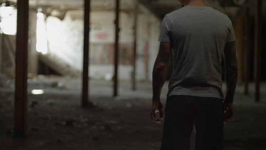 A man is standing in the interior of an abandoned building