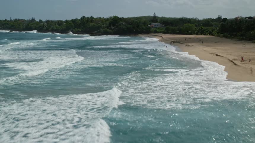 Aerial view of a tropical beach next to the ocean waves