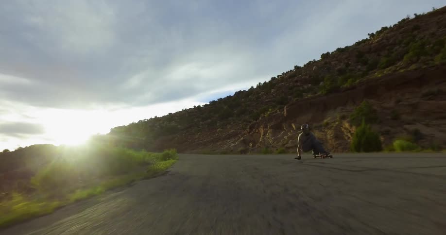 A skateboarder speeds down a rural mountain road