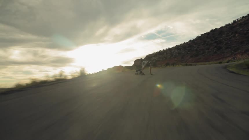 A man is racing down a road on a skateboard