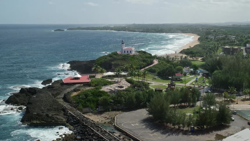 A coastal region with some buildings surrounded by trees and a trail full of stones