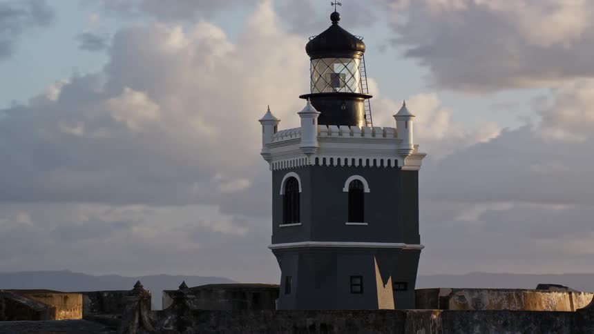 A historical lighthouse with a domed top and a cloudy sky